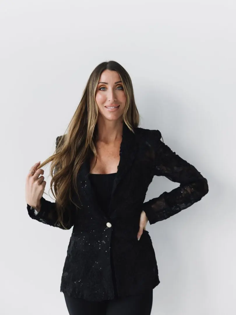 Confident woman in a black blazer with long hair smiles gently.